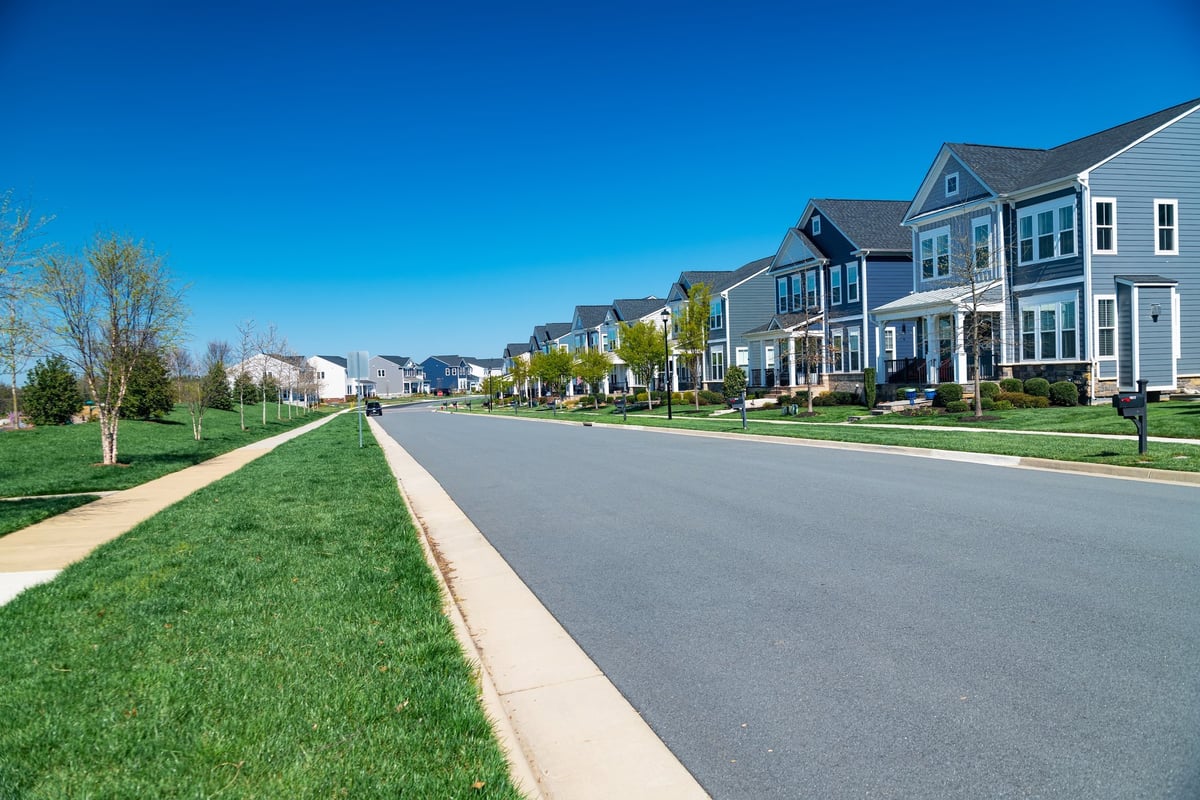 Row of modern detached houses with lawns and sidewalks in a residential area