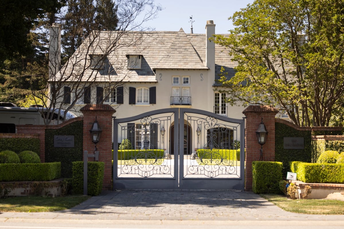 Gated luxury mansion with wrought-iron detailing and manicured grounds