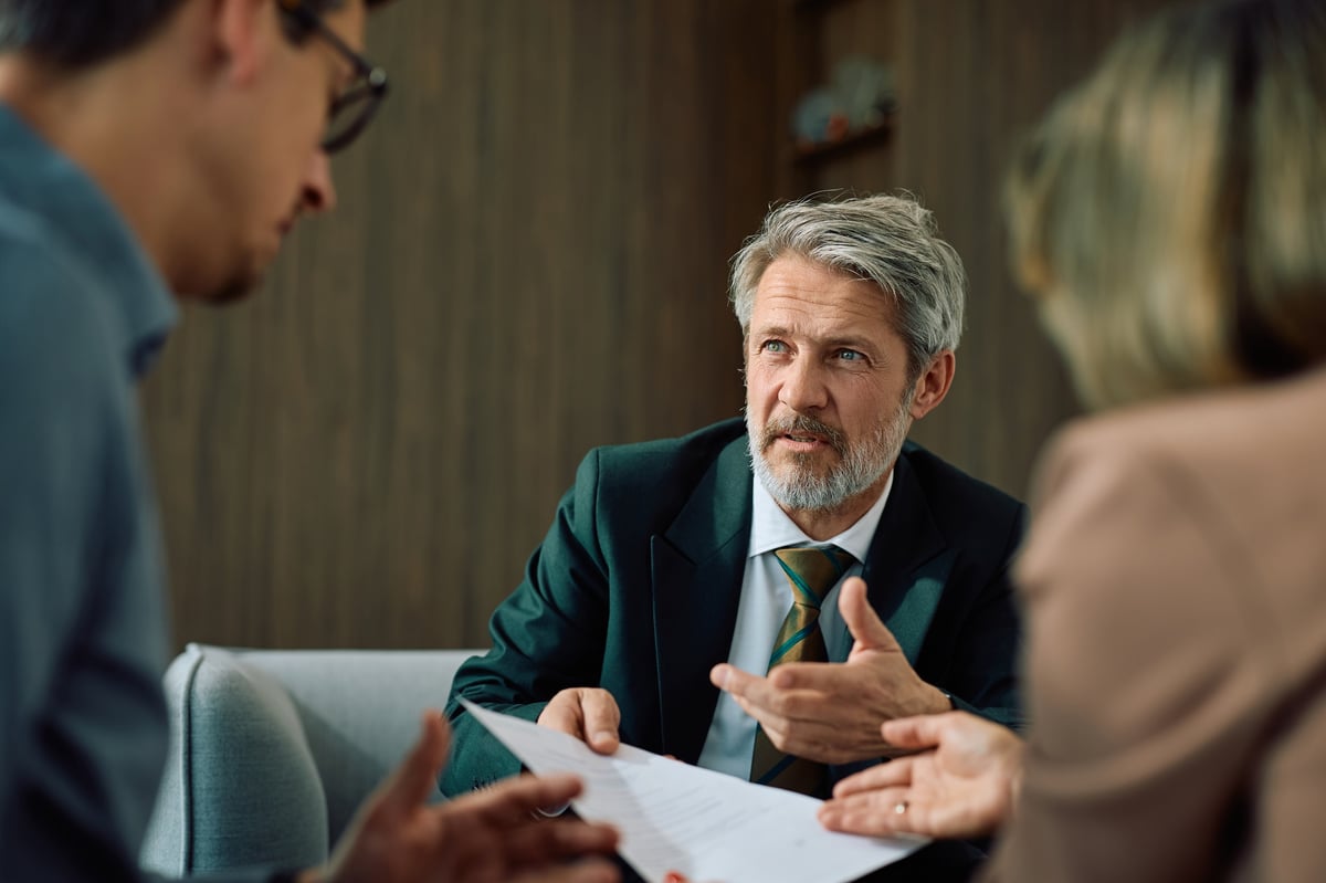 Senior loan officer reviewing campus-area housing financing documents with clients