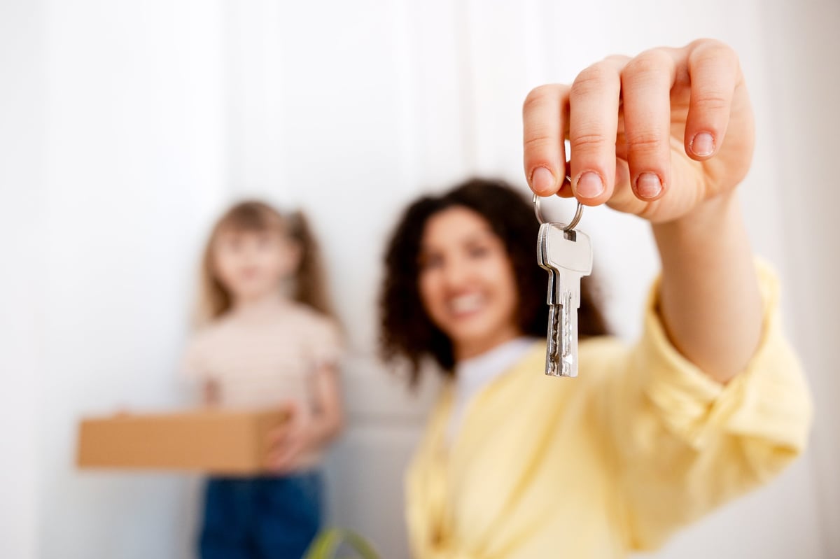 Parent and college-age student with house keys and moving boxes — evaluating ownership near Florida State University instead of paying rent