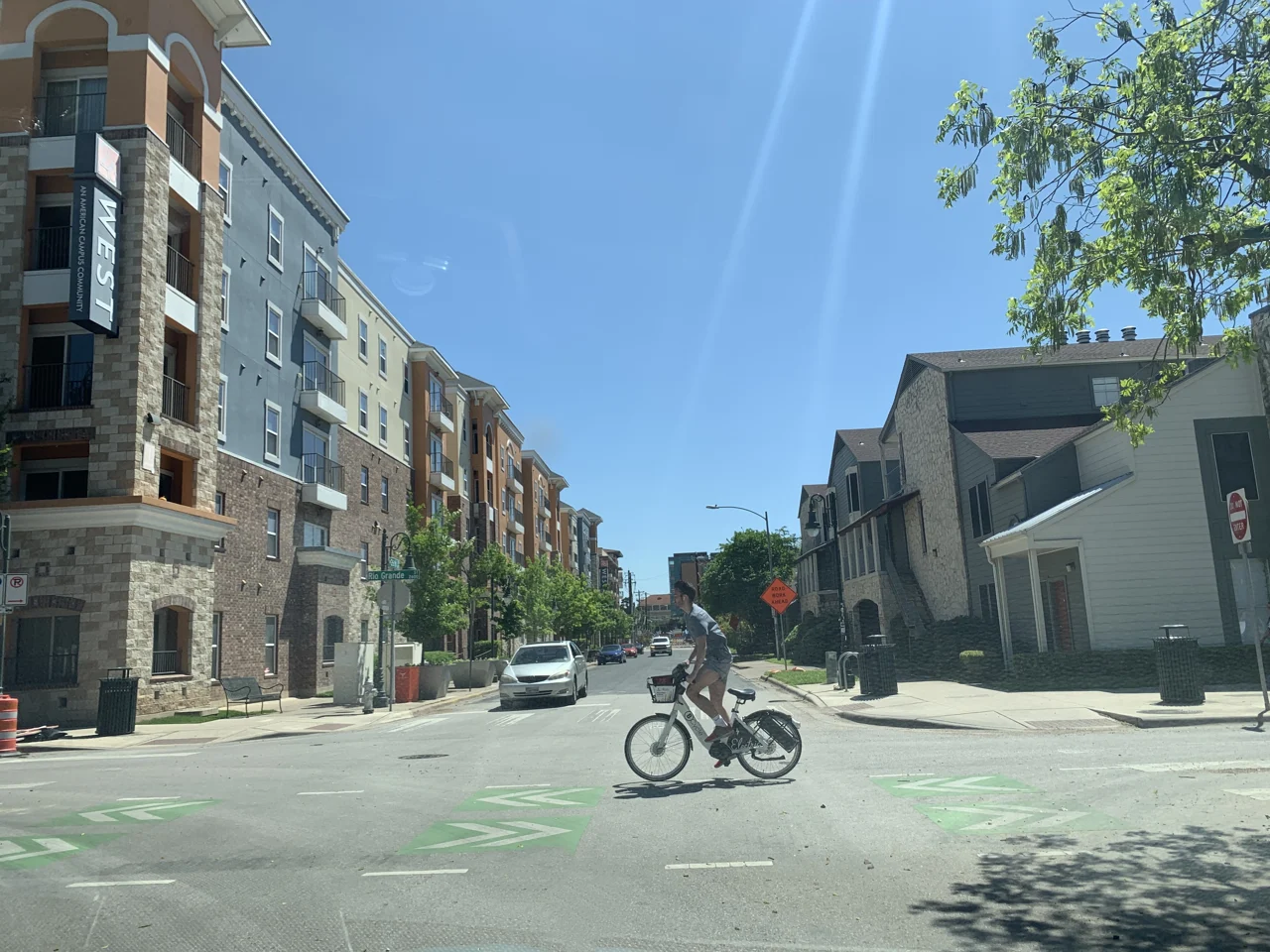 A cyclist crosses an intersection between apartment buildings in West Campus, Austin.