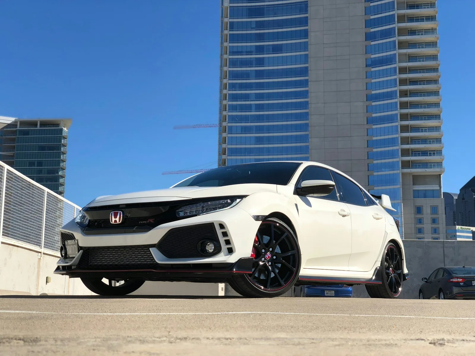 A white Honda parked near modern buildings in Dallas. Illustrative photography, not a local listing.