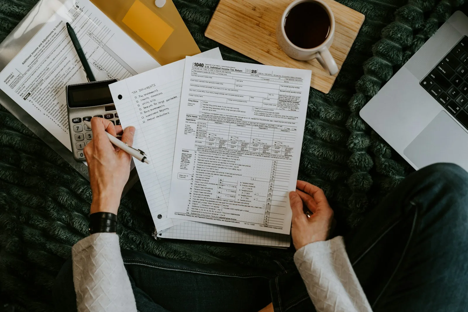 Hands reviewing paperwork beside a calculator and laptop. Illustrative photography, not a local listing.