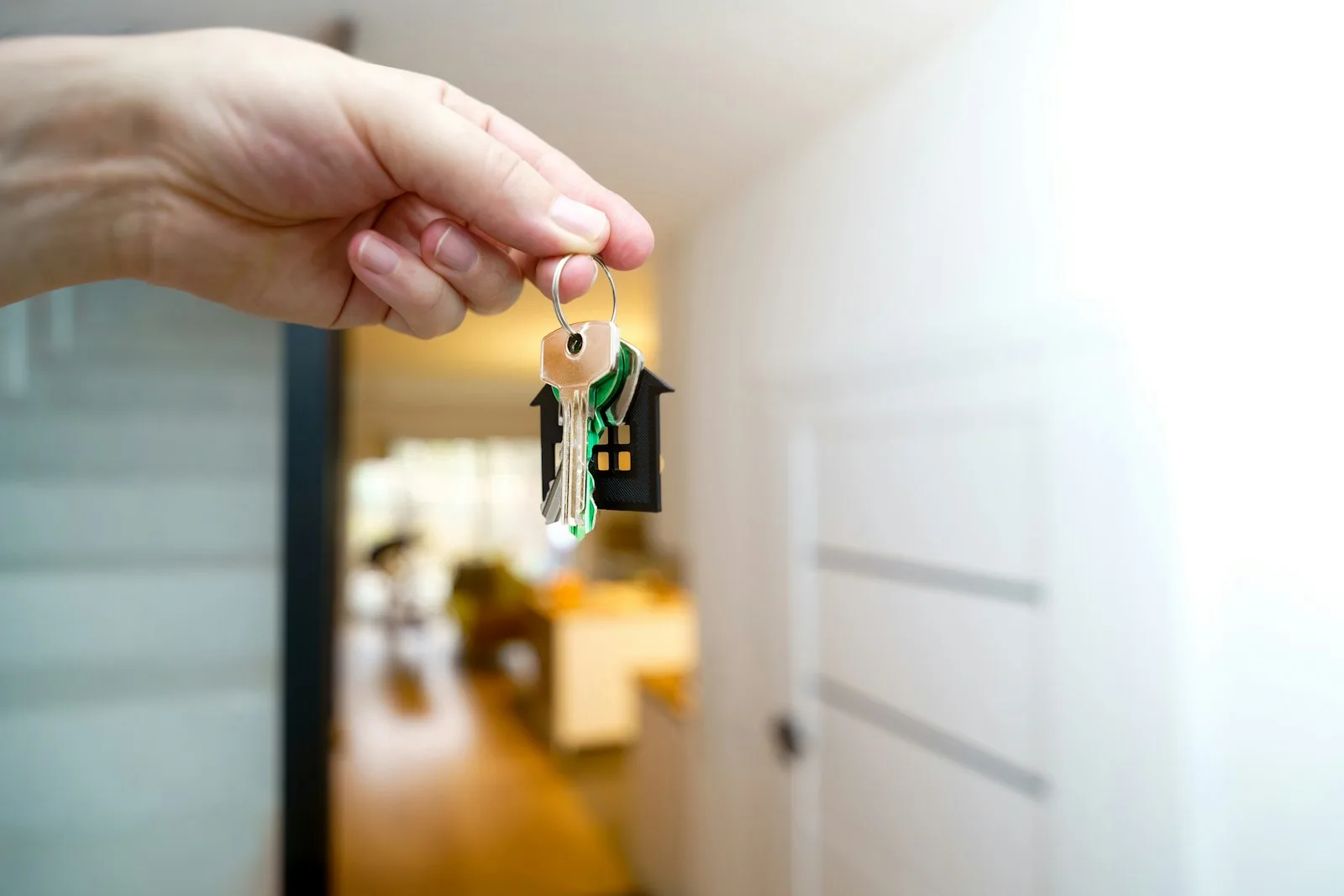 A hand holding a home key in an entrance. Illustrative photography, not a local listing.