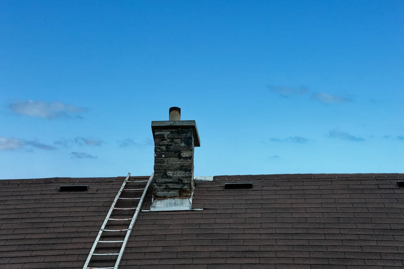A roof, chimney and ladder against a blue sky. Illustrative photography, not a local listing.