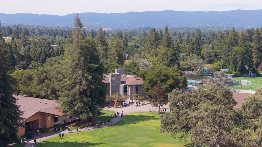 Aerial view of Menlo College’s Atherton campus, with the central quad, academic buildings and athletic fields among the trees.